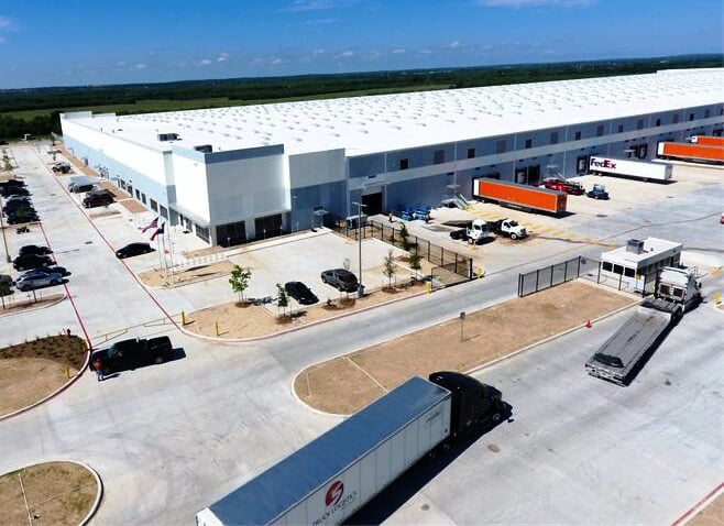 Large, flat building with shipping trailers parked at loading docks